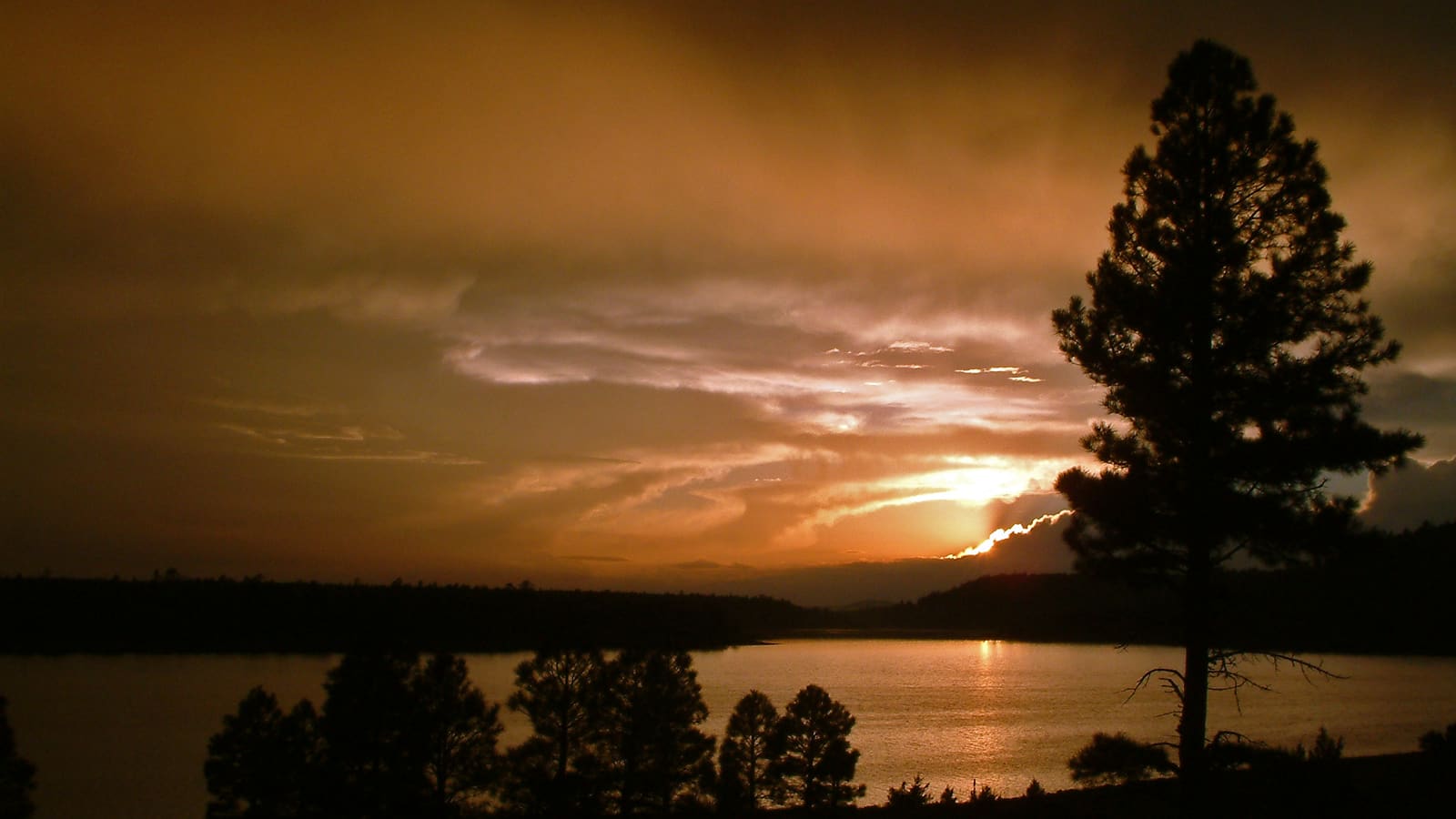 The sun setting behind clouds over Upper Lake Mary near Flagstaff