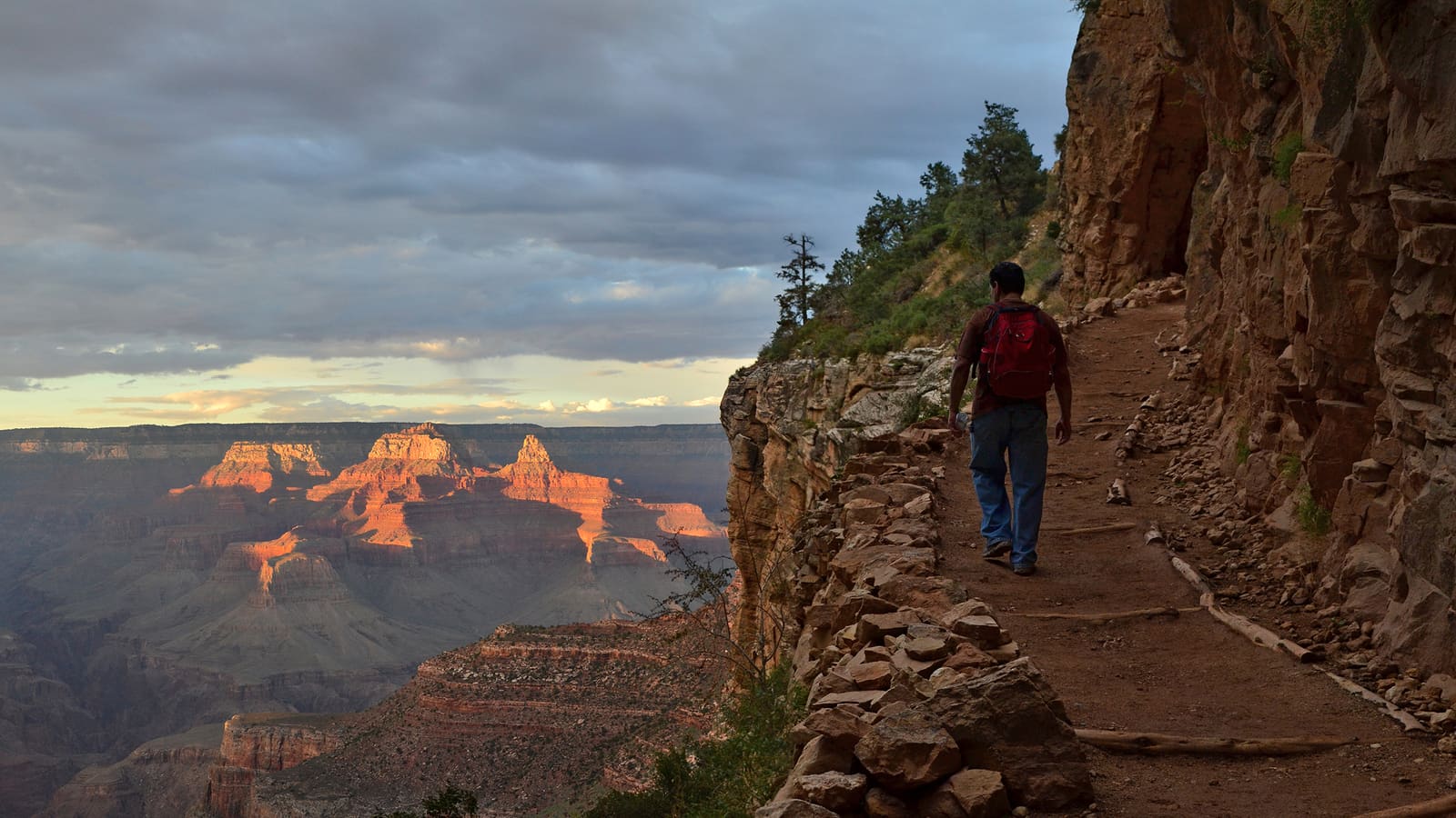 A hiker on the Bright Angel Trail below the Grand Canyon's South Rim at sunset