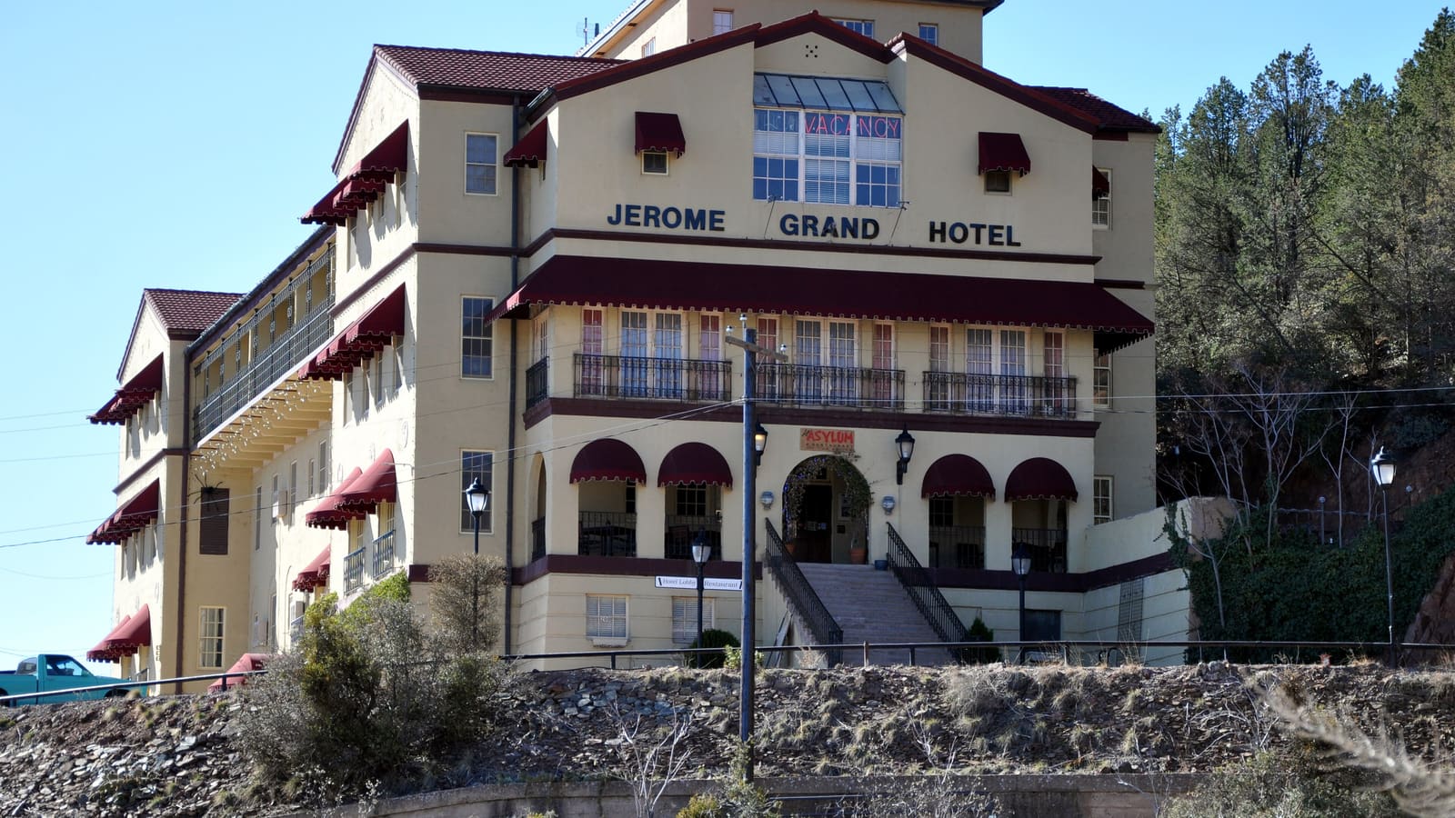 Exterior view of the Jerome Grand Hotel, a large brick former hospital building perched on a hillside above Jerome, Arizona, reputed to be one of the most haunted hotels in America.