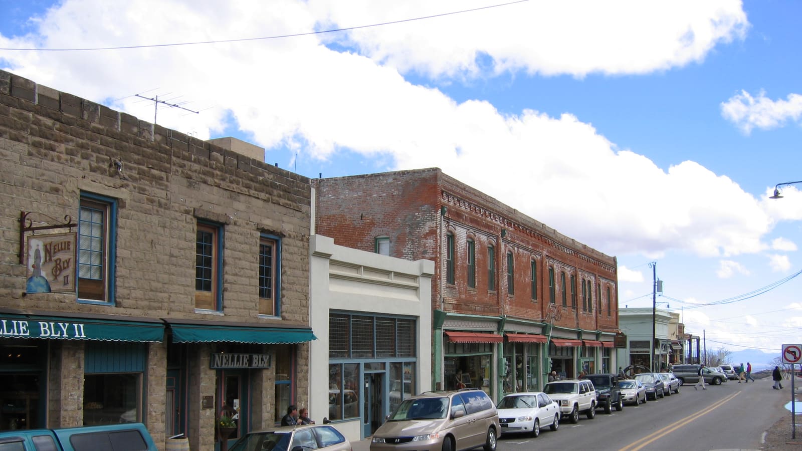 A row of historic brick storefronts and buildings lining a narrow, hilly street in downtown Jerome, Arizona.