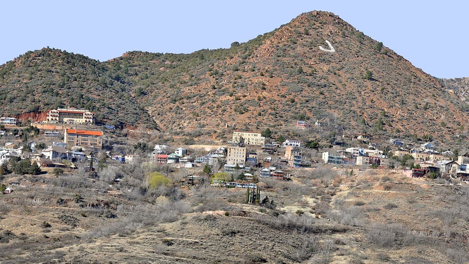 A wide panoramic view of Jerome, Arizona, showing the town's buildings terraced up the slope of Cleopatra Hill above the Verde Valley.