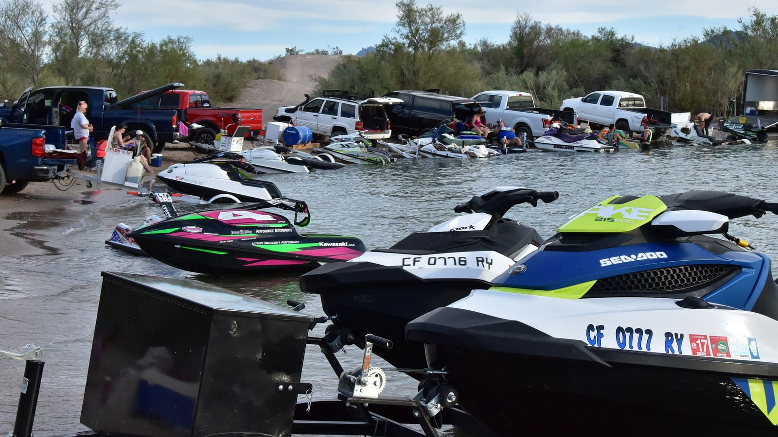 Personal watercraft and tow vehicles gathered along a Lake Havasu shoreline in Arizona