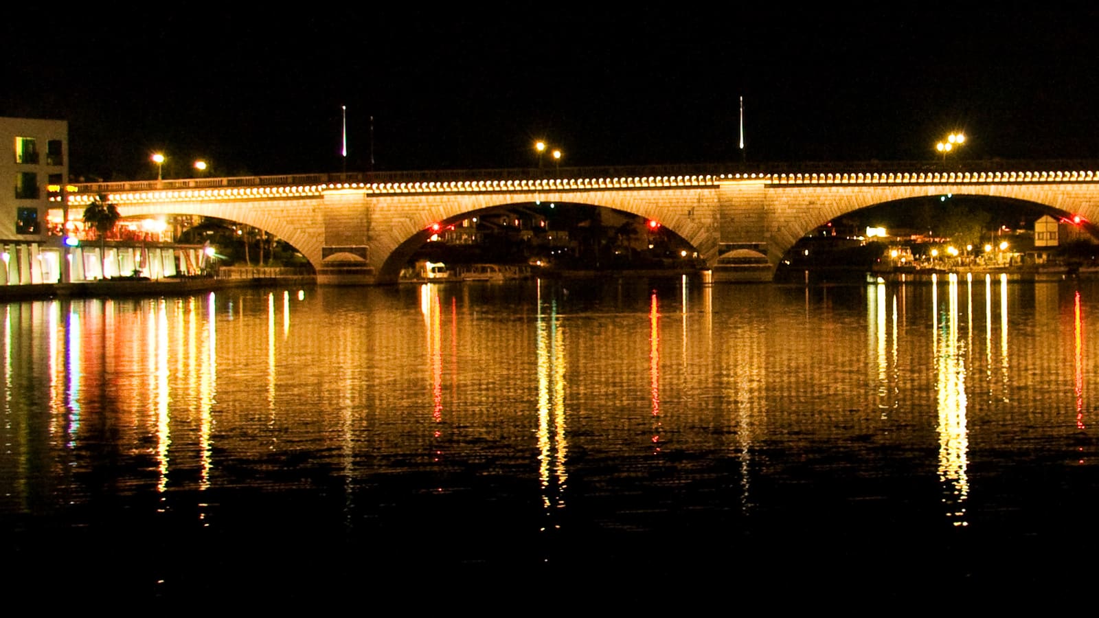 The London Bridge lit up at night over the Lake Havasu City channel, reflected in the water