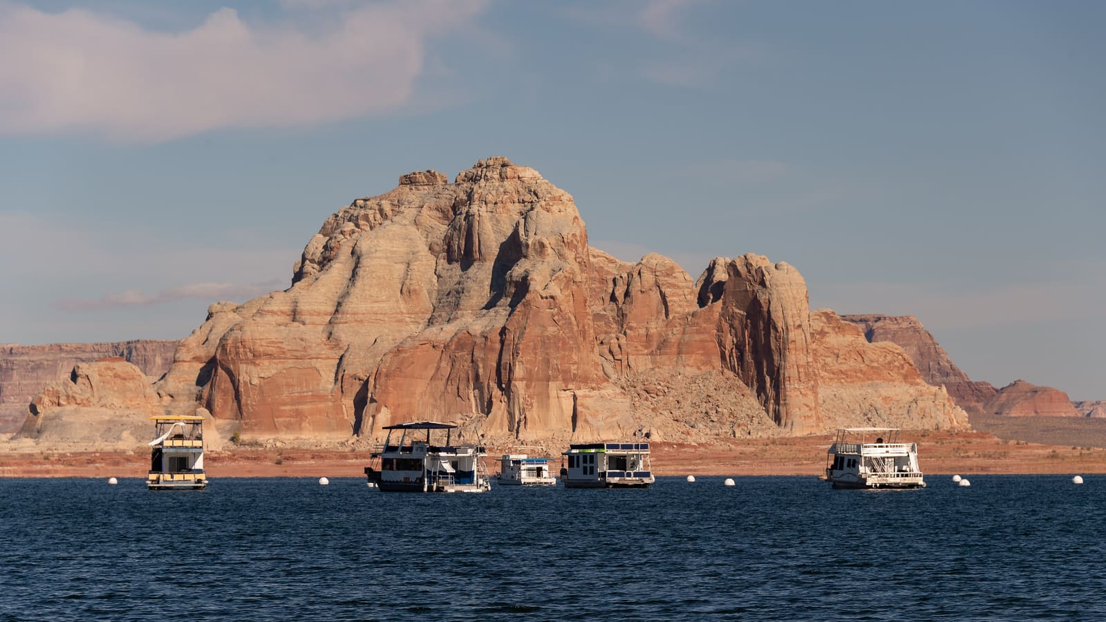Houseboats moored below sandstone cliffs on Lake Powell