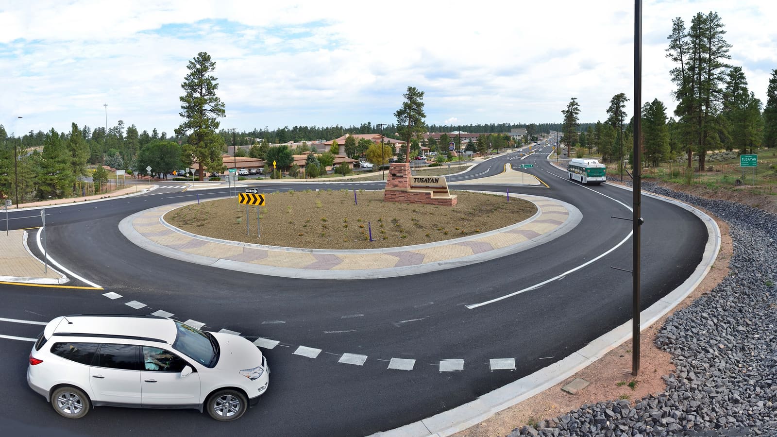 The Tusayan entrance monument and roundabout on AZ-64, with hotels and ponderosa pine forest in the gateway town south of Grand Canyon National Park